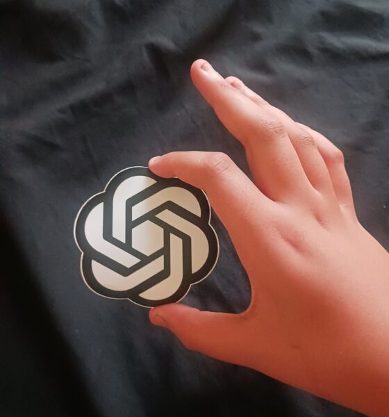 Main tenant un autocollant du logo d'OpenAI