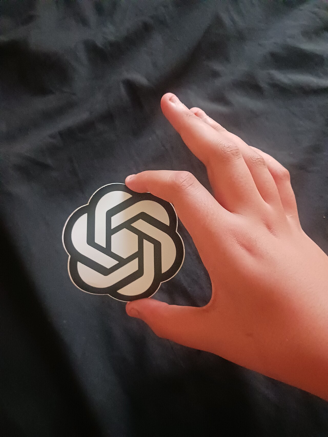 Main tenant un autocollant du logo d'OpenAI