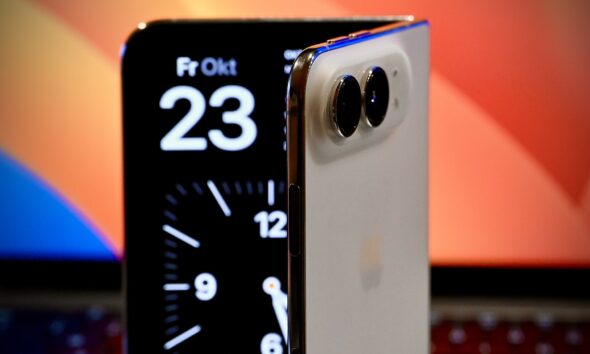 iPhone Duo à moitié ouvert posé devant un MacBook Pro