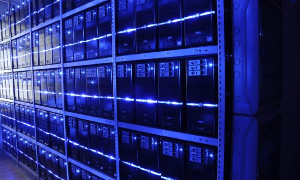 Allée de baies de serveurs éclairées en bleu dans un data center