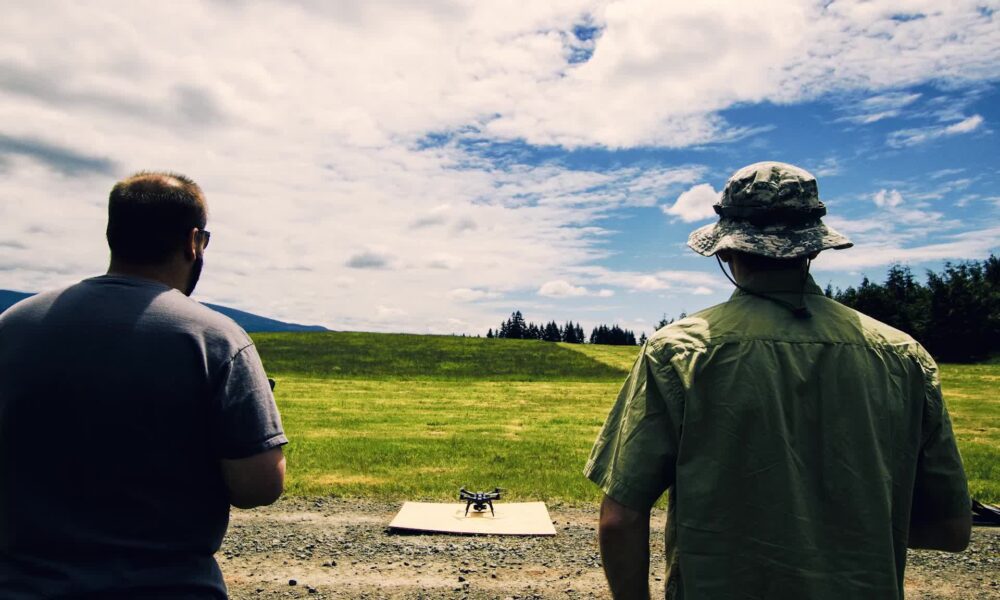 Deux télépilotes observent un drone posé sur une plateforme avant un vol d'entraînement