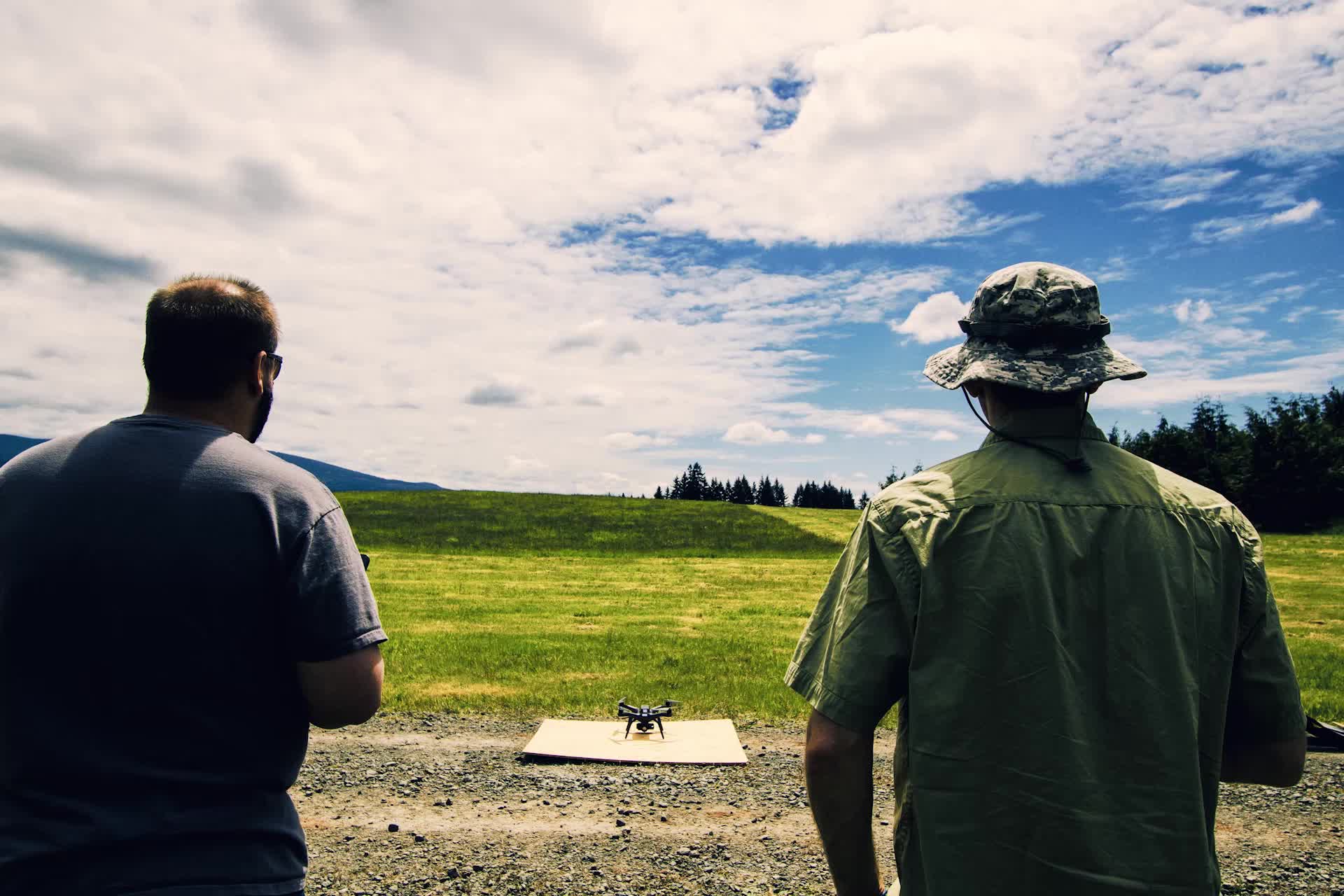 Deux télépilotes observent un drone posé sur une plateforme avant un vol d'entraînement